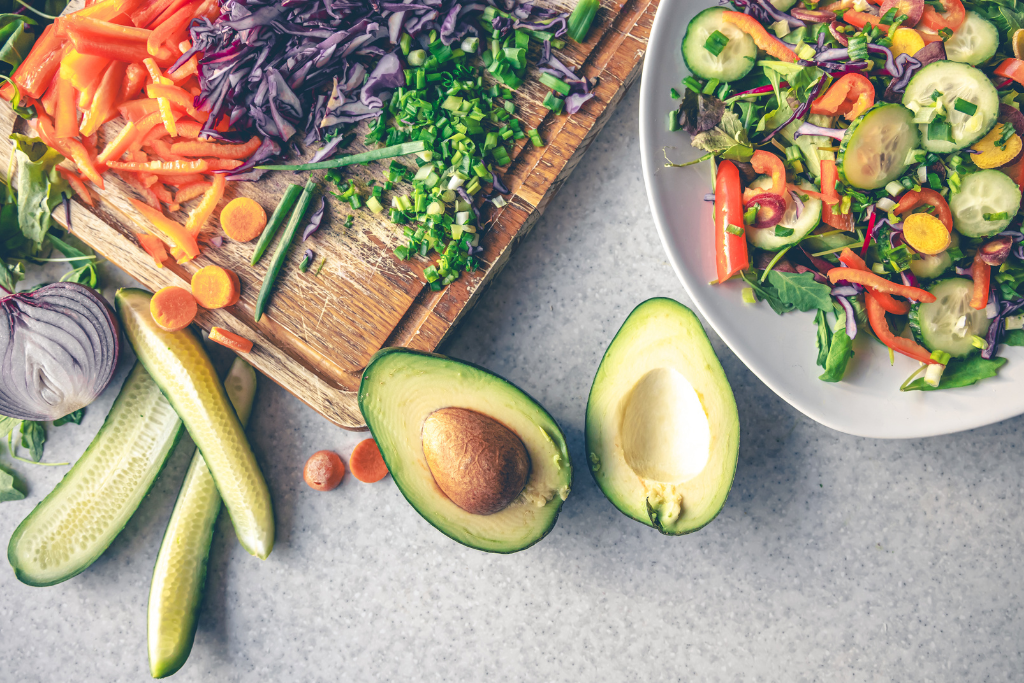 Świeże warzywa niskowęglowodanowe na wegańskiej diecie ketogenicznej – awokado, ogórek, czerwona kapusta, marchew, szczypiorek i zielone liście przygotowane do roślinnego posiłku keto.